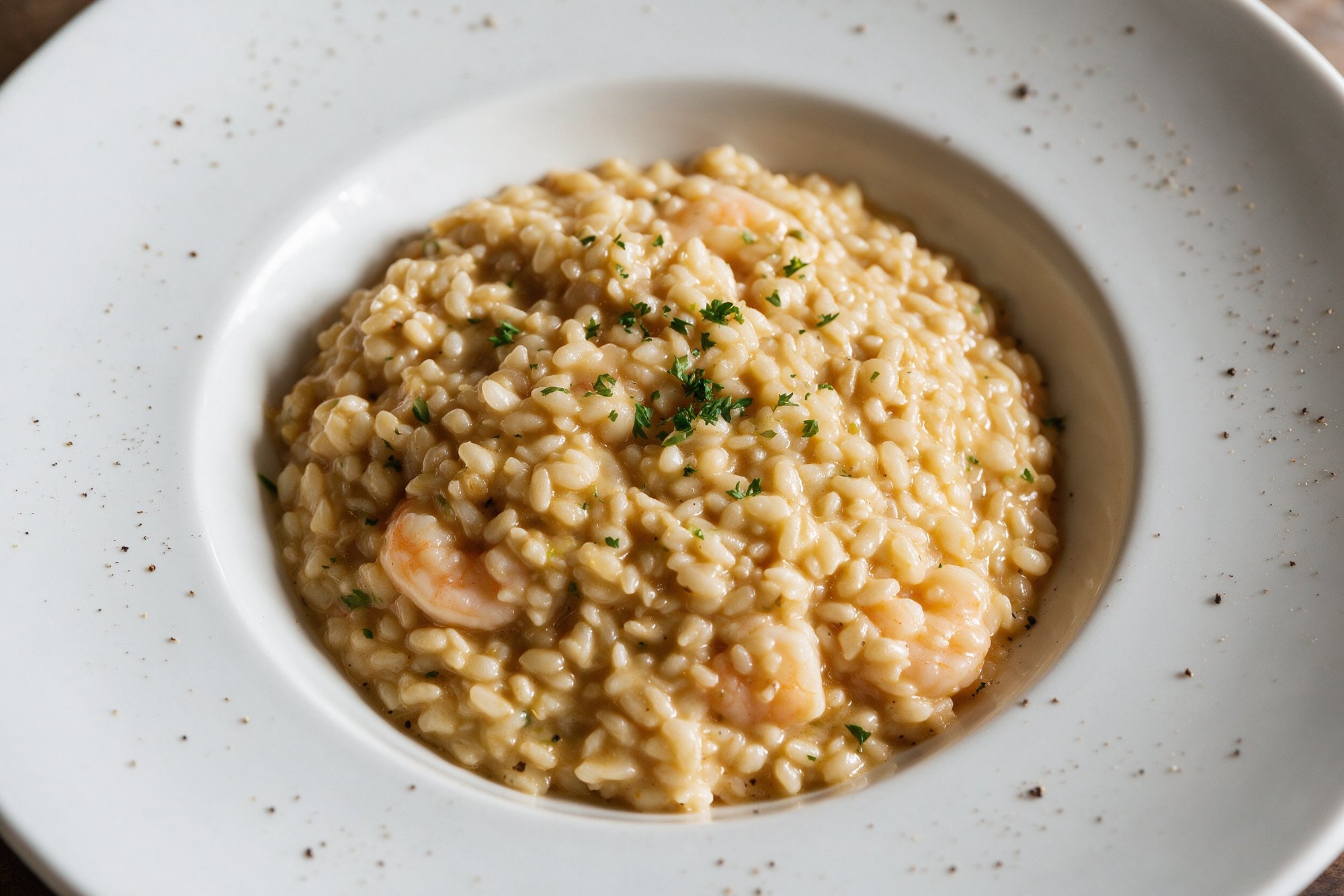 Risotto cremoso de camarones con perejil en plato hondo